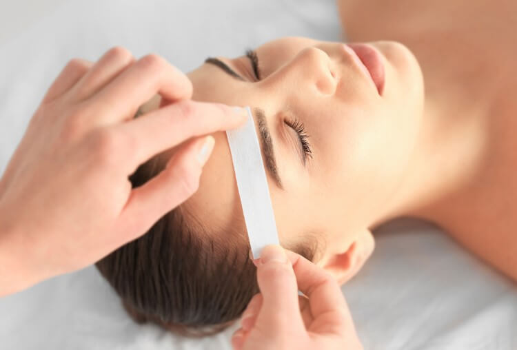 Applying a hair removal strip to a person's face.